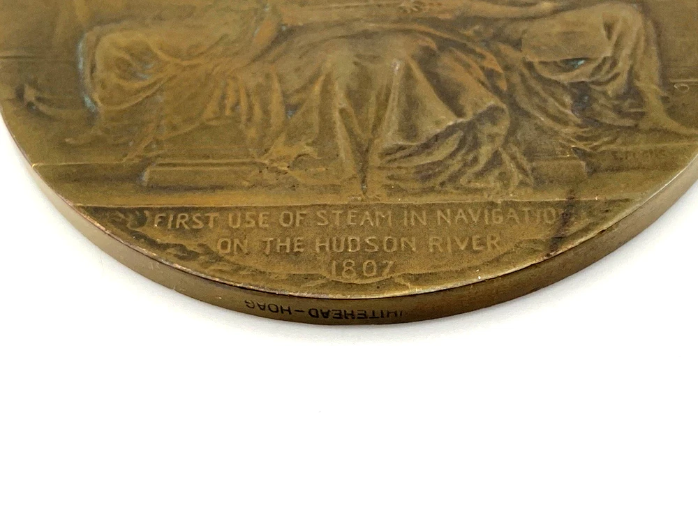 1909 Hudson-Fulton bronze medal showing Robert Fulton’s portrait above three seated allegorical women and a model steamboat.