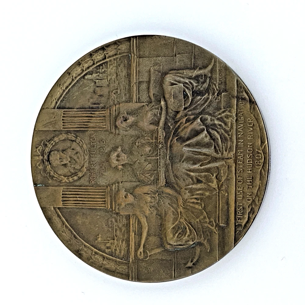 1909 Hudson-Fulton bronze medal showing Robert Fulton’s portrait above three seated allegorical women and a model steamboat.