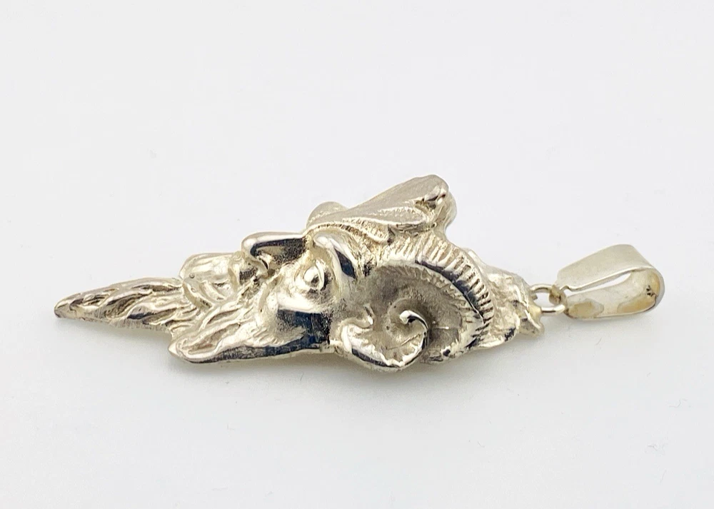 Sterling silver pendant showing a bearded mythological figure with curled ram horns, an acanthus leaf between the horns, a pointed beard, and a broad bail.