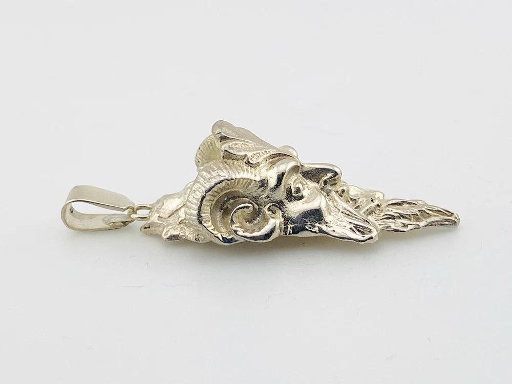 Sterling silver pendant showing a bearded mythological figure with curled ram horns, an acanthus leaf between the horns, a pointed beard, and a broad bail.