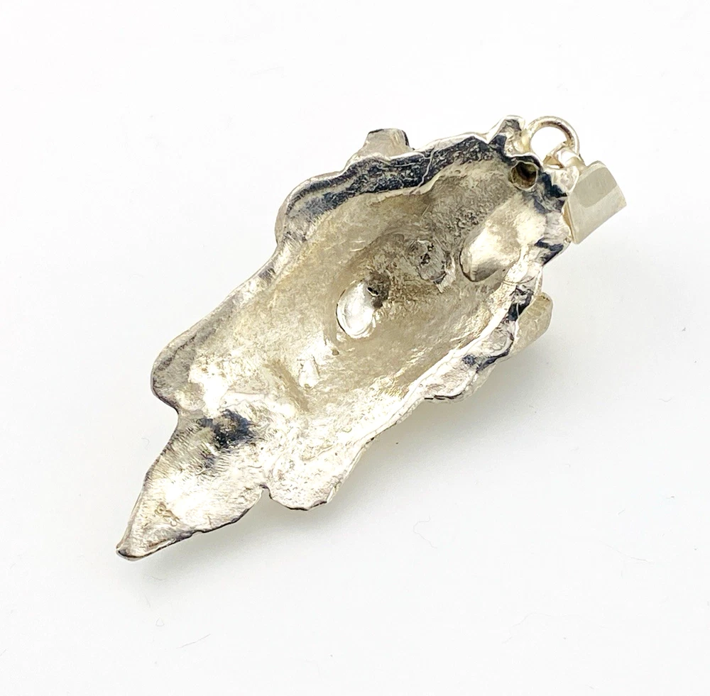 Sterling silver pendant showing a bearded mythological figure with curled ram horns, an acanthus leaf between the horns, a pointed beard, and a broad bail.