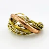 Sculptural unisex cuff bracelet with intertwined brass wires, a textured copper arc, silver-colored molten-drop accents, and rounded ball terminals.