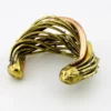 Sculptural unisex cuff bracelet with intertwined brass wires, a textured copper arc, silver-colored molten-drop accents, and rounded ball terminals.
