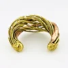 Sculptural unisex cuff bracelet with intertwined brass wires, a textured copper arc, silver-colored molten-drop accents, and rounded ball terminals.