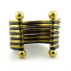 Wide cuff bracelet with alternating golden brass and near-black copper bands, four round brass finials, and small areas of wear to the darkened finish.