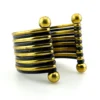 Wide cuff bracelet with alternating golden brass and near-black copper bands, four round brass finials, and small areas of wear to the darkened finish.