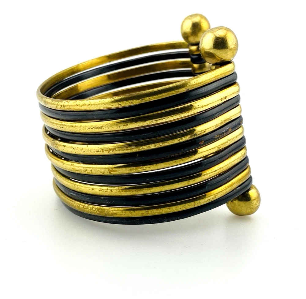 Wide cuff bracelet with alternating golden brass and near-black copper bands, four round brass finials, and small areas of wear to the darkened finish.