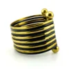 Wide cuff bracelet with alternating golden brass and near-black copper bands, four round brass finials, and small areas of wear to the darkened finish.