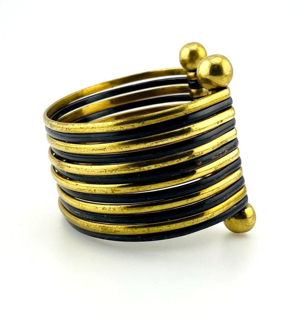 Wide cuff bracelet with alternating golden brass and near-black copper bands, four round brass finials, and small areas of wear to the darkened finish.