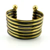 Wide cuff bracelet with alternating golden brass and near-black copper bands, four round brass finials, and small areas of wear to the darkened finish.