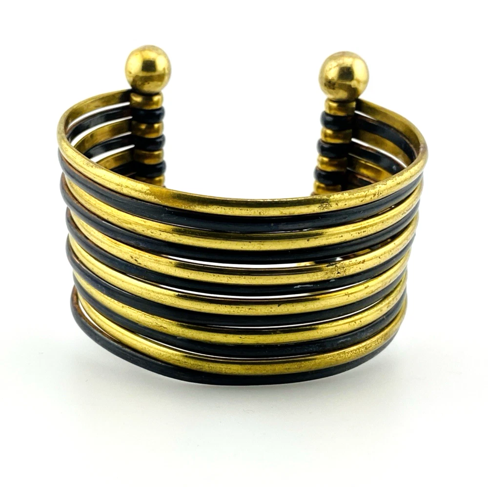 Wide cuff bracelet with alternating golden brass and near-black copper bands, four round brass finials, and small areas of wear to the darkened finish.
