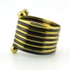 Wide cuff bracelet with alternating golden brass and near-black copper bands, four round brass finials, and small areas of wear to the darkened finish.