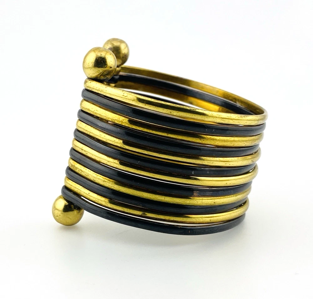 Wide cuff bracelet with alternating golden brass and near-black copper bands, four round brass finials, and small areas of wear to the darkened finish.