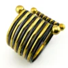 Wide cuff bracelet with alternating golden brass and near-black copper bands, four round brass finials, and small areas of wear to the darkened finish.