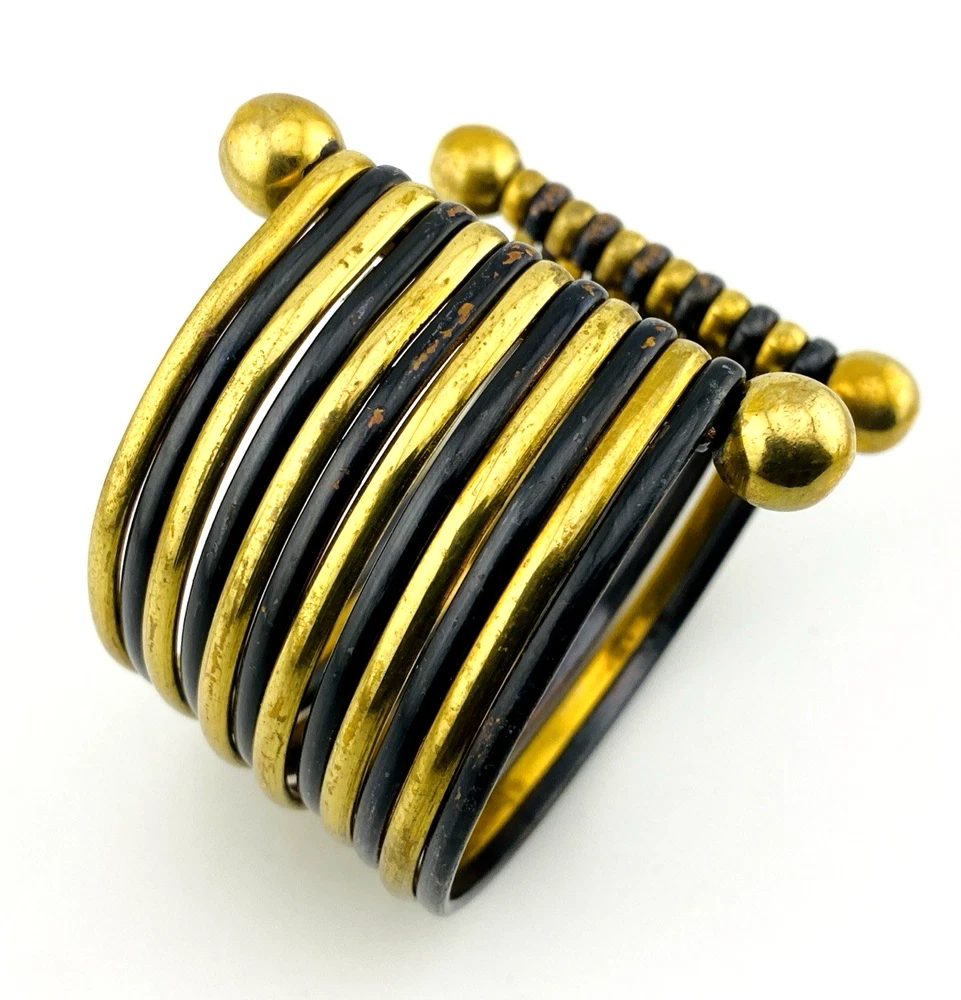 Wide cuff bracelet with alternating golden brass and near-black copper bands, four round brass finials, and small areas of wear to the darkened finish.