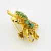 Gold-plated sterling silver bee brooch with a green gemstone-set body, clear cubic zirconia accent, raised patterned wings, and textured legs.