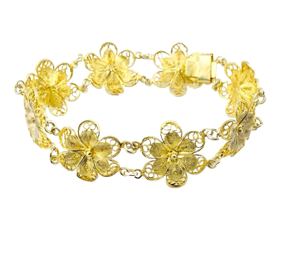 Pale gold-over-silver bracelet with eight six-petal filigree flowers, raised bead centers, and paired connecting links.