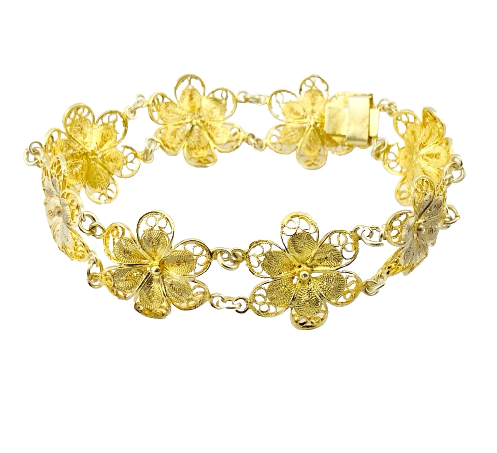 Pale gold-over-silver bracelet with eight six-petal filigree flowers, raised bead centers, and paired connecting links.