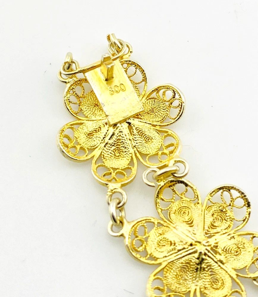 Pale gold-over-silver bracelet with eight six-petal filigree flowers, raised bead centers, and paired connecting links.