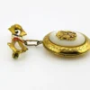 Gold-plated WWII sweetheart locket brooch with an eagle-and-shield emblem on mother of pearl, engraved border, and red, white, and blue enameled bow.