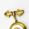 Gold-plated WWII sweetheart locket brooch with an eagle-and-shield emblem on mother of pearl, engraved border, and red, white, and blue enameled bow.