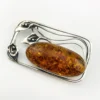 Circa 1990s sterling silver brooch with a large oval cognac amber cabochon and three calla lilies forming an open rectangular frame.