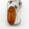 Circa 1990s sterling silver brooch with a large oval cognac amber cabochon and three calla lilies forming an open rectangular frame.