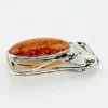 Circa 1990s sterling silver brooch with a large oval cognac amber cabochon and three calla lilies forming an open rectangular frame.