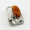 Circa 1990s sterling silver brooch with a large oval cognac amber cabochon and three calla lilies forming an open rectangular frame.