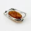 Circa 1990s sterling silver brooch with a large oval cognac amber cabochon and three calla lilies forming an open rectangular frame.