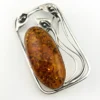 Circa 1990s sterling silver brooch with a large oval cognac amber cabochon and three calla lilies forming an open rectangular frame.