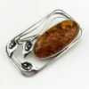 Circa 1990s sterling silver brooch with a large oval cognac amber cabochon and three calla lilies forming an open rectangular frame.