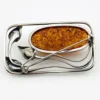 Circa 1990s sterling silver brooch with a large oval cognac amber cabochon and three calla lilies forming an open rectangular frame.