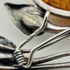 Circa 1990s sterling silver brooch with a large oval cognac amber cabochon and three calla lilies forming an open rectangular frame.