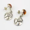 Amber stud earrings with dangling sterling silver flowers, showing one golden yellow cabochon and one deeper orange cabochon.