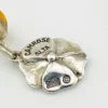 Amber stud earrings with dangling sterling silver flowers, showing one golden yellow cabochon and one deeper orange cabochon.