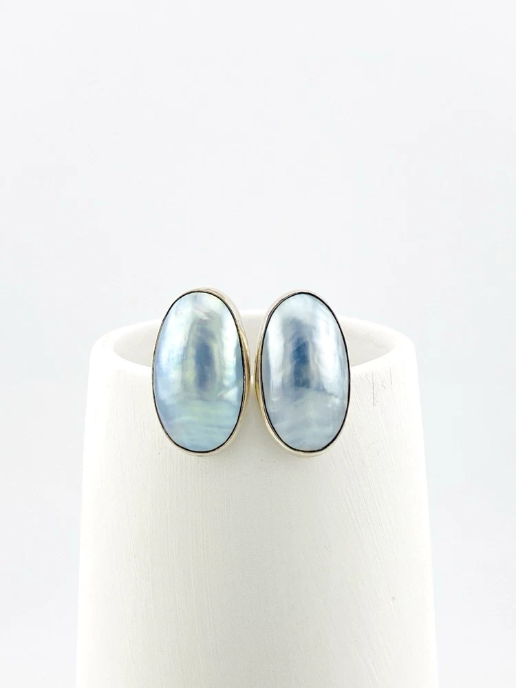 Great Falls Metal Works oval light blue mabé pearl earrings in narrow sterling silver bezels, shown upright from the front.