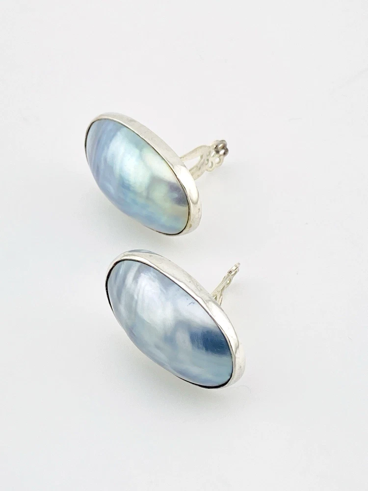 Great Falls Metal Works oval light blue mabé pearl earrings in narrow sterling silver bezels, shown upright from the front.