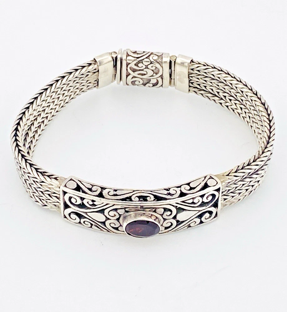 Multistrand silver bracelet with square woven chains, curved scrollwork panel, oval garnet and decorated box clasp