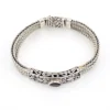 Multistrand silver bracelet with square woven chains, curved scrollwork panel, oval garnet and decorated box clasp