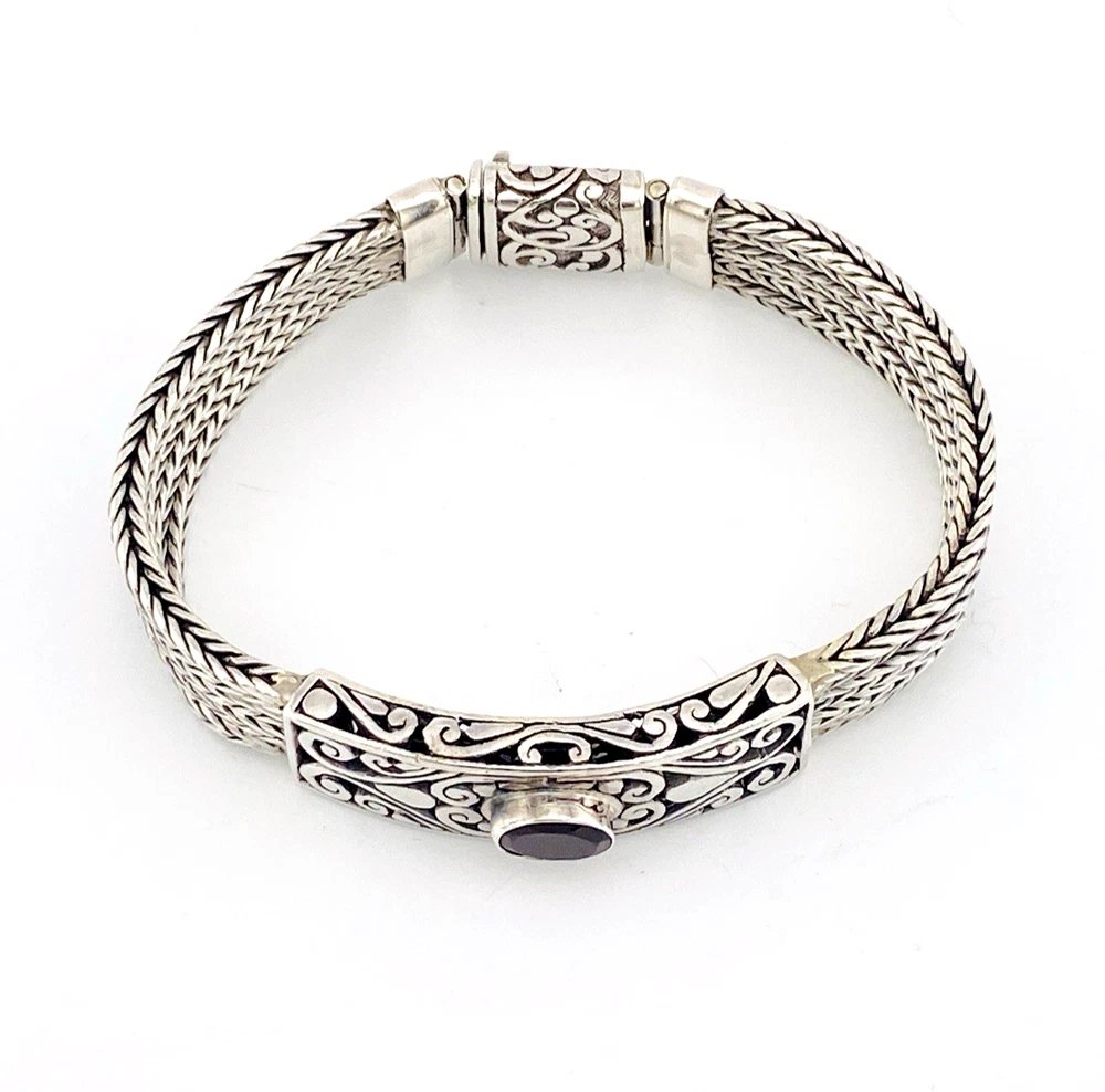 Multistrand silver bracelet with square woven chains, curved scrollwork panel, oval garnet and decorated box clasp