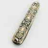 Vintage sterling silver needle case with raised cabbage roses, curling scrollwork, darkened recesses, and a suspension loop on the cap.