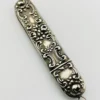 Vintage sterling silver needle case with raised cabbage roses, curling scrollwork, darkened recesses, and a suspension loop on the cap.