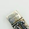 Vintage sterling silver needle case with raised cabbage roses, curling scrollwork, darkened recesses, and a suspension loop on the cap.