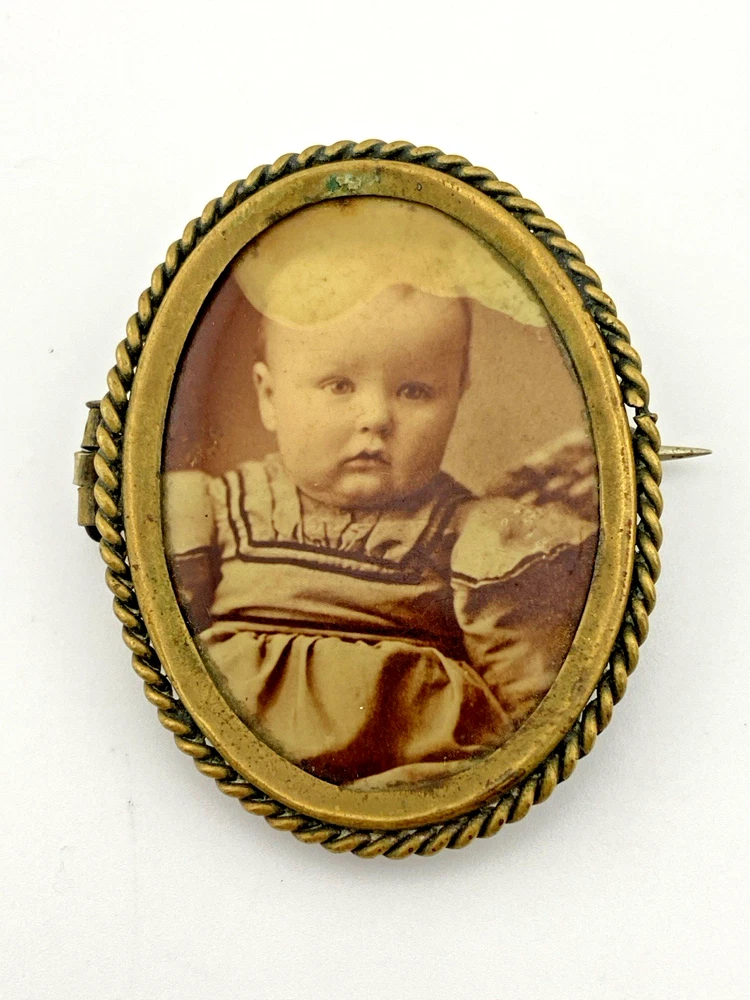 Two antique gold-tone rope-border brooches: a round faded portrait of a woman and an oval tintype portrait of a young child.