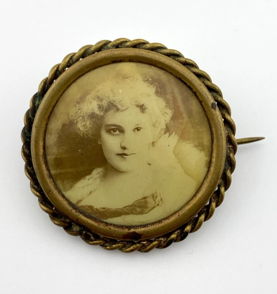 Two antique gold-tone rope-border brooches: a round faded portrait of a woman and an oval tintype portrait of a young child.