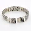 Multistrand silver bracelet with square woven chains, curved scrollwork panel, oval garnet and decorated box clasp