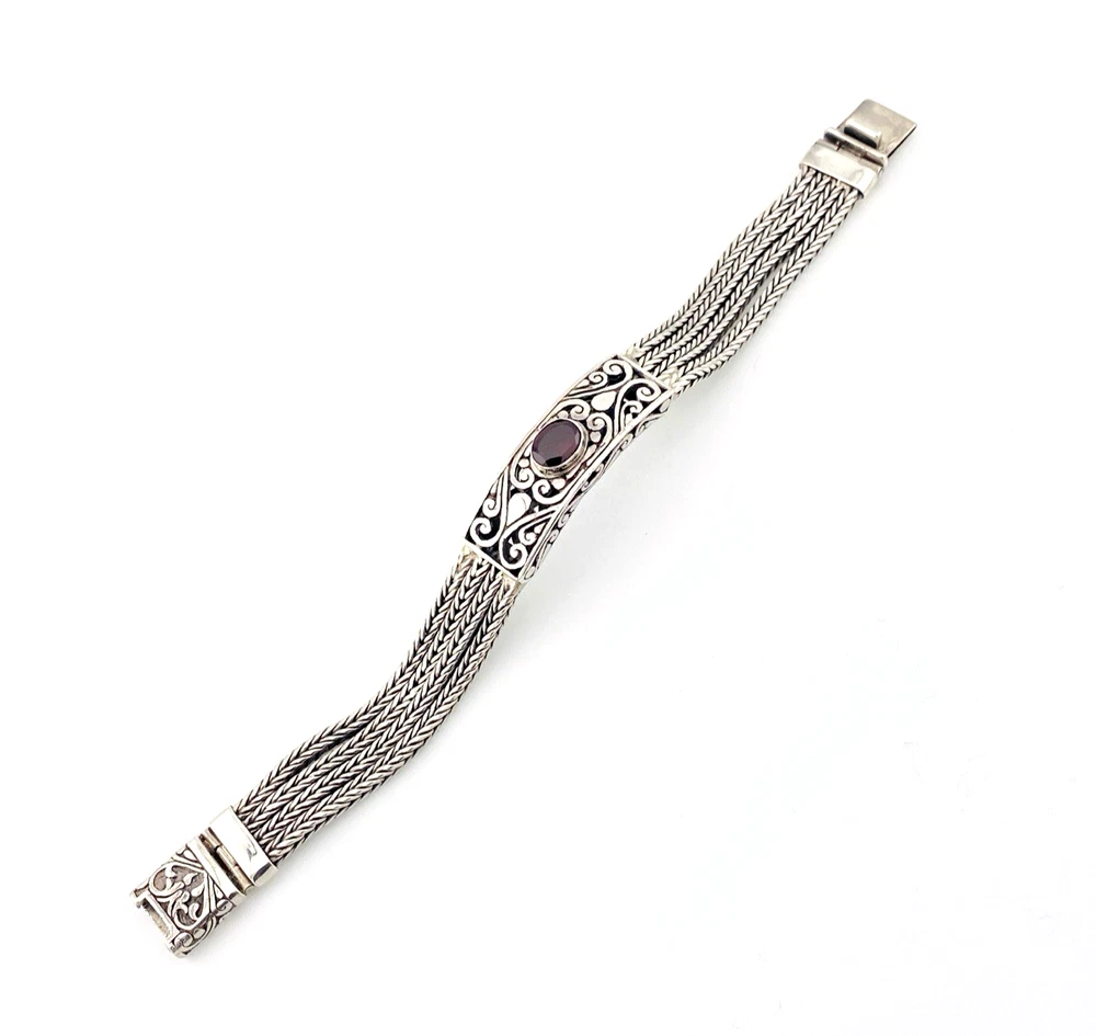 Multistrand silver bracelet with square woven chains, curved scrollwork panel, oval garnet and decorated box clasp