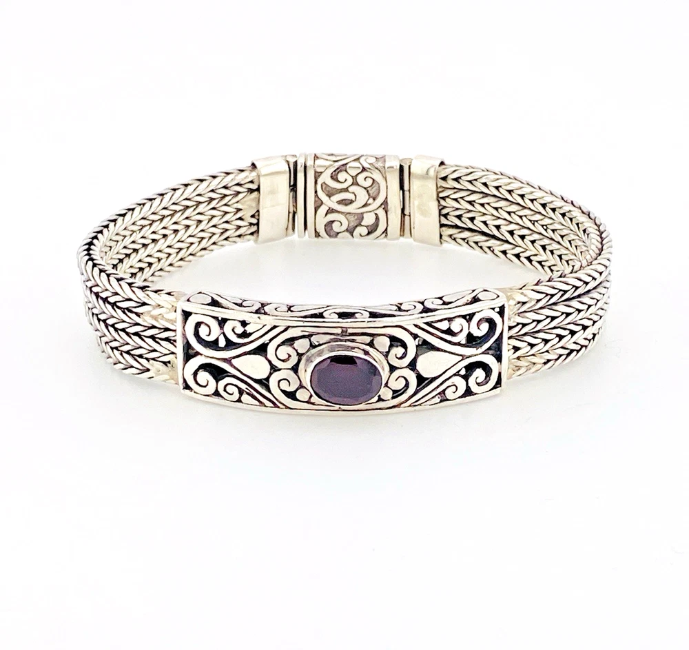 Multistrand silver bracelet with square woven chains, curved scrollwork panel, oval garnet and decorated box clasp
