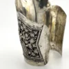 Wide peaked silver cuff with three crowned celestial dancers, openwork leafy scrolls and a rounded longevity medallion